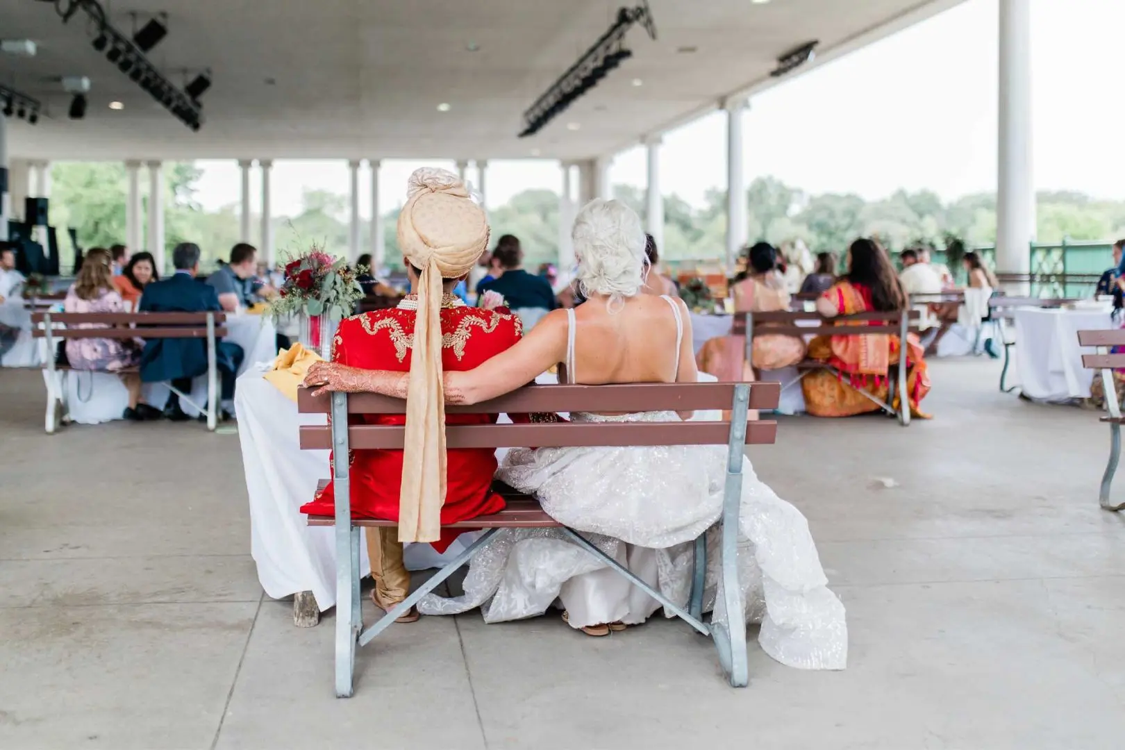 Back shot of groom and bride sitting on a bench on the promenade