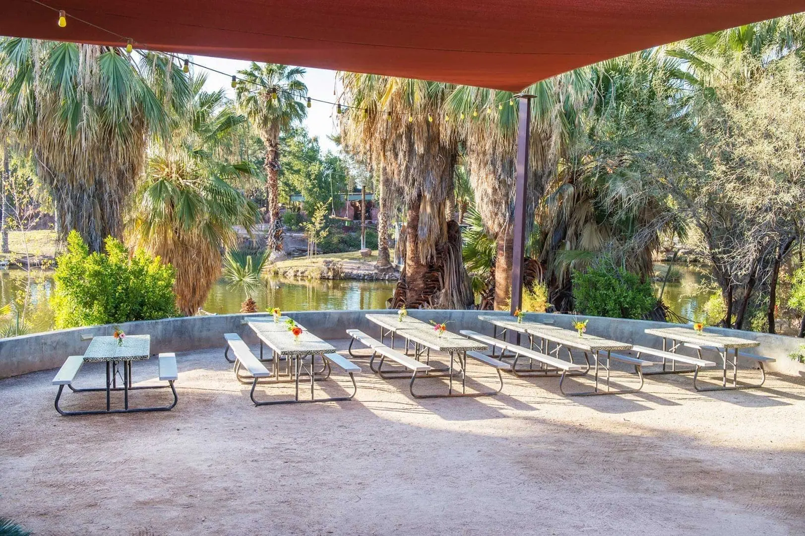 Picnic tables underneath sun shade overlooking water