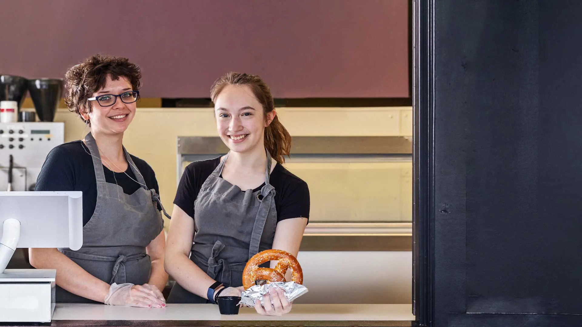 Two employees smiling behind counter