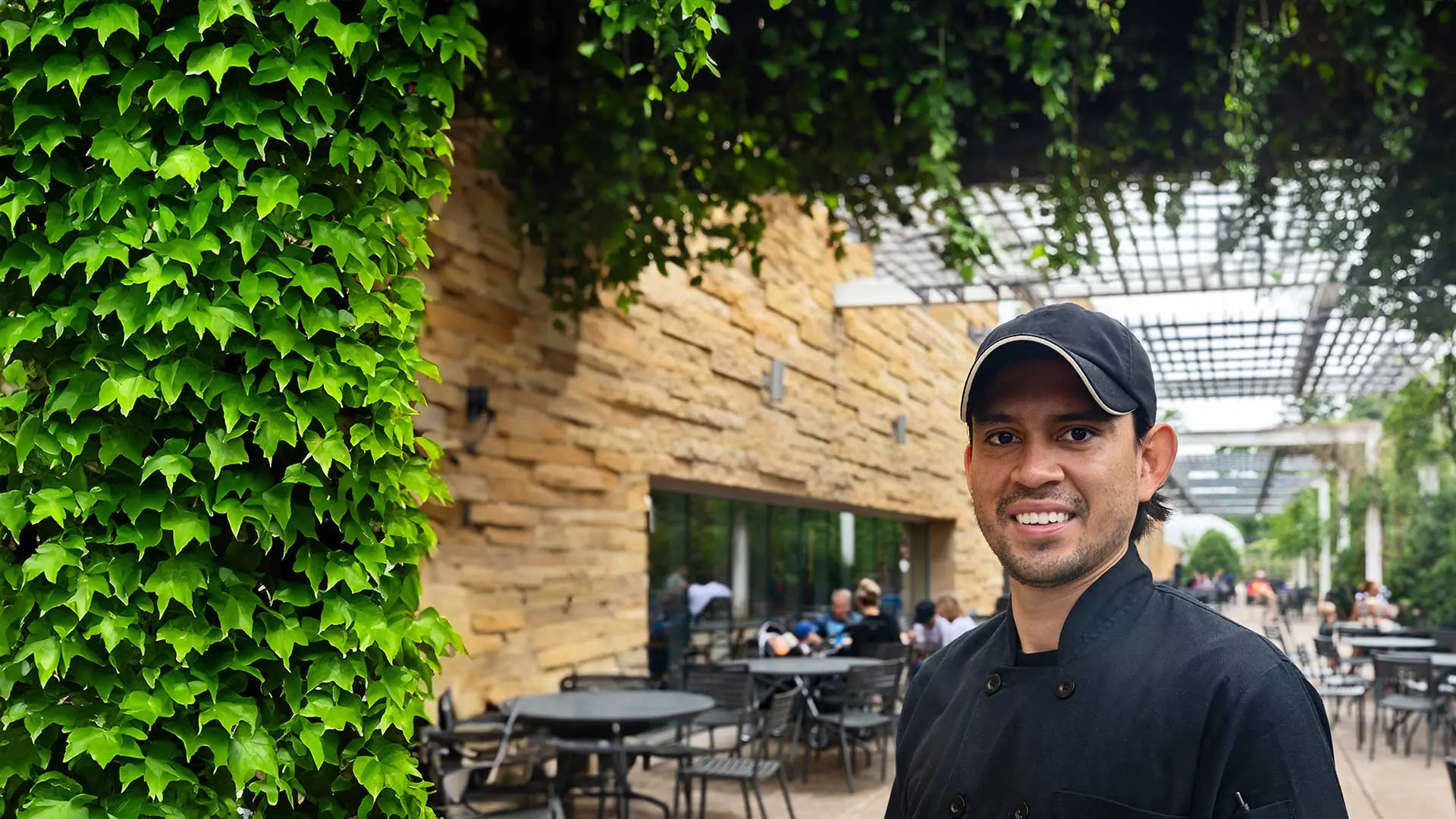 Employee smiling underneath canopy of ivy