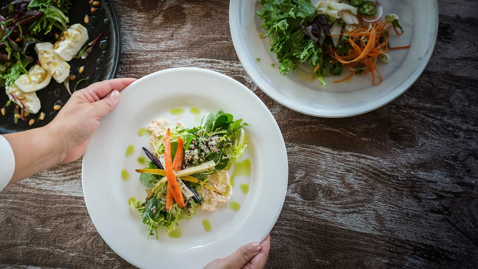 Overhead shot of hands placing dish on wood table