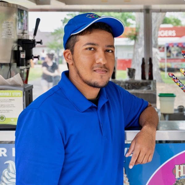 Employee looking at camera while leaning on food cart