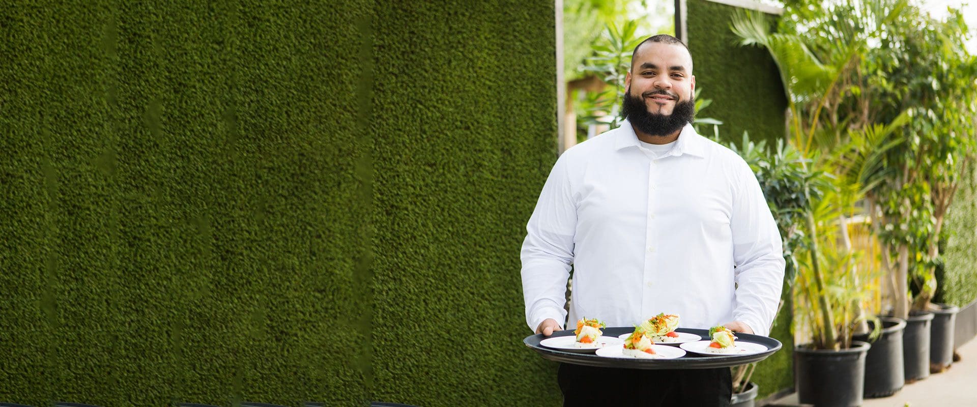 Waiter holding tray of food while smiling at camera