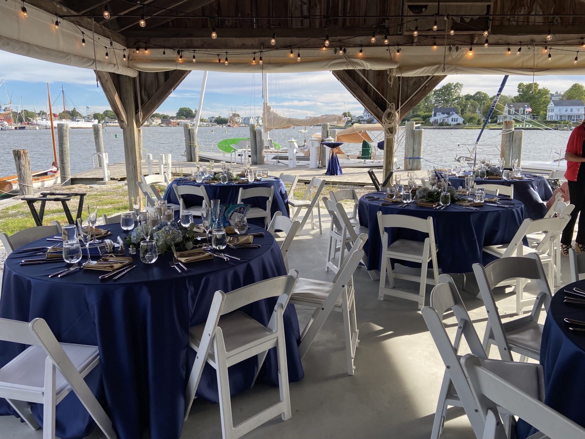 Decorated event tables underneath pavilion with view of water and docks