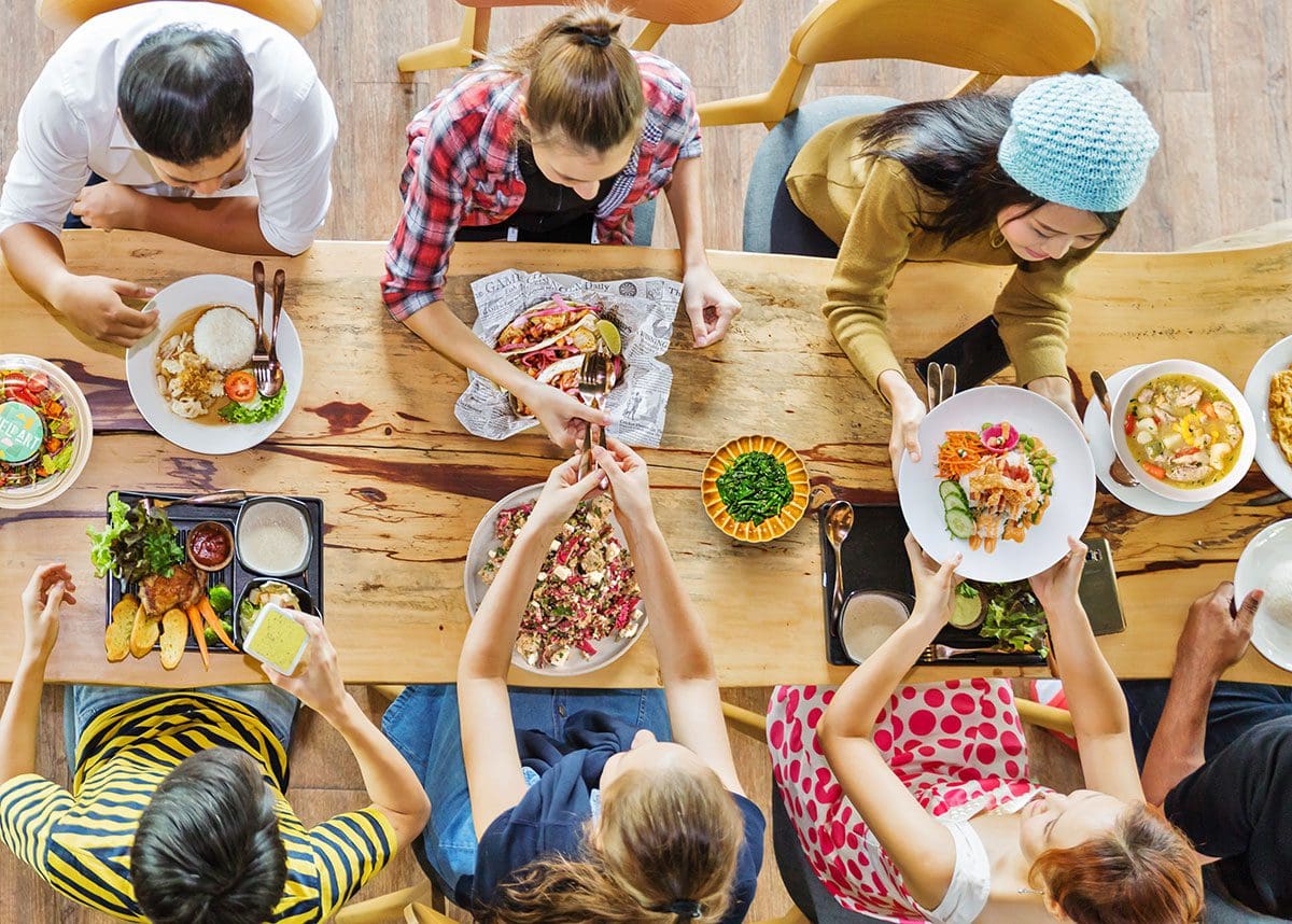 Overhead shot of people eating at table, each with a different dish