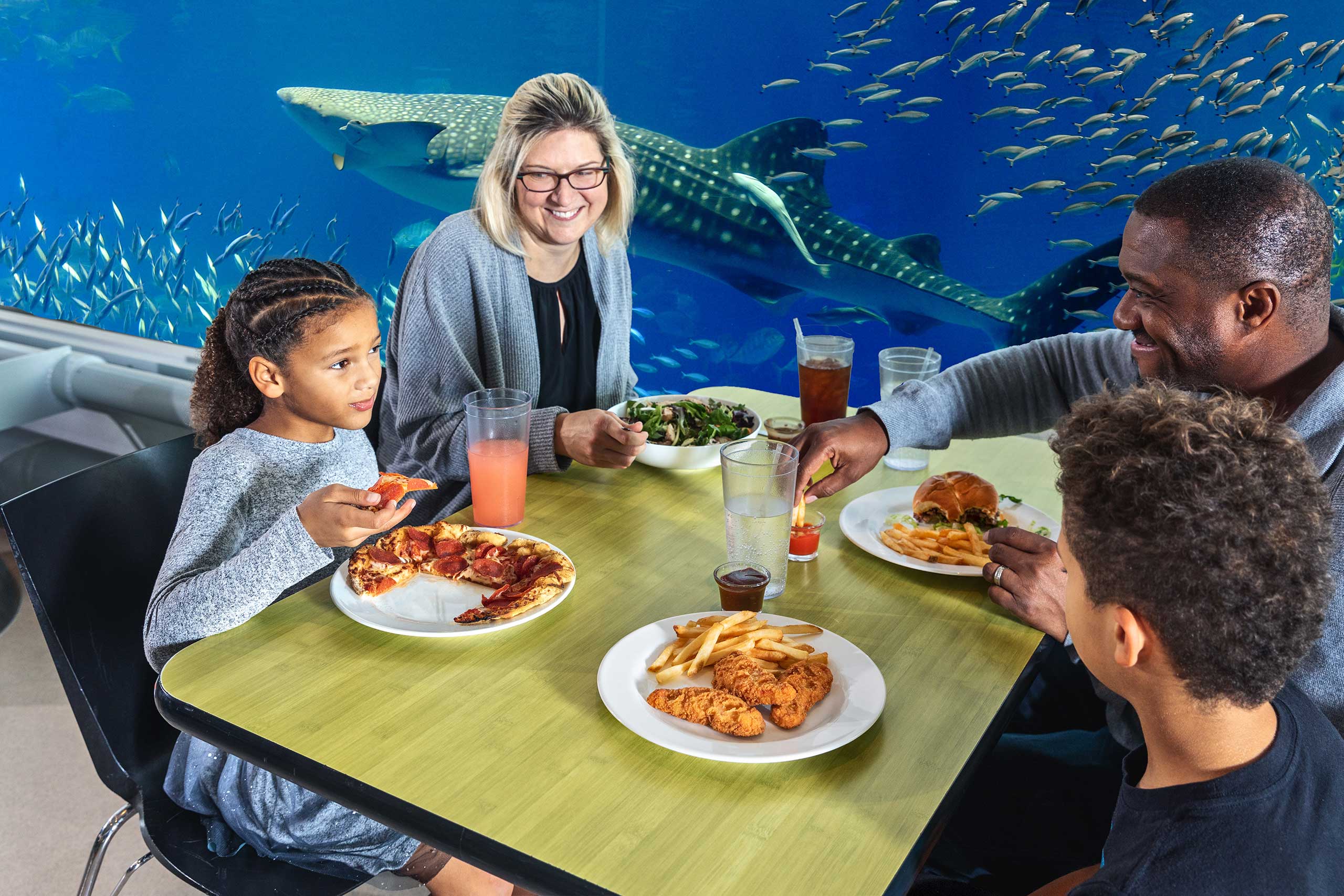 Family eating lunch in front of aquarium at museum