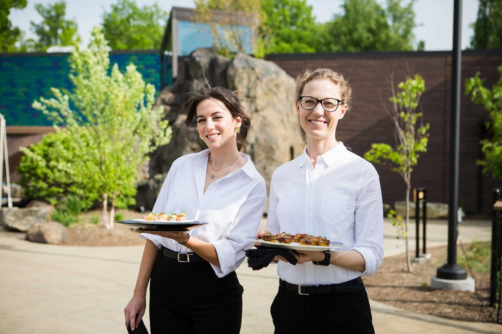Two servers holding trays and smiling