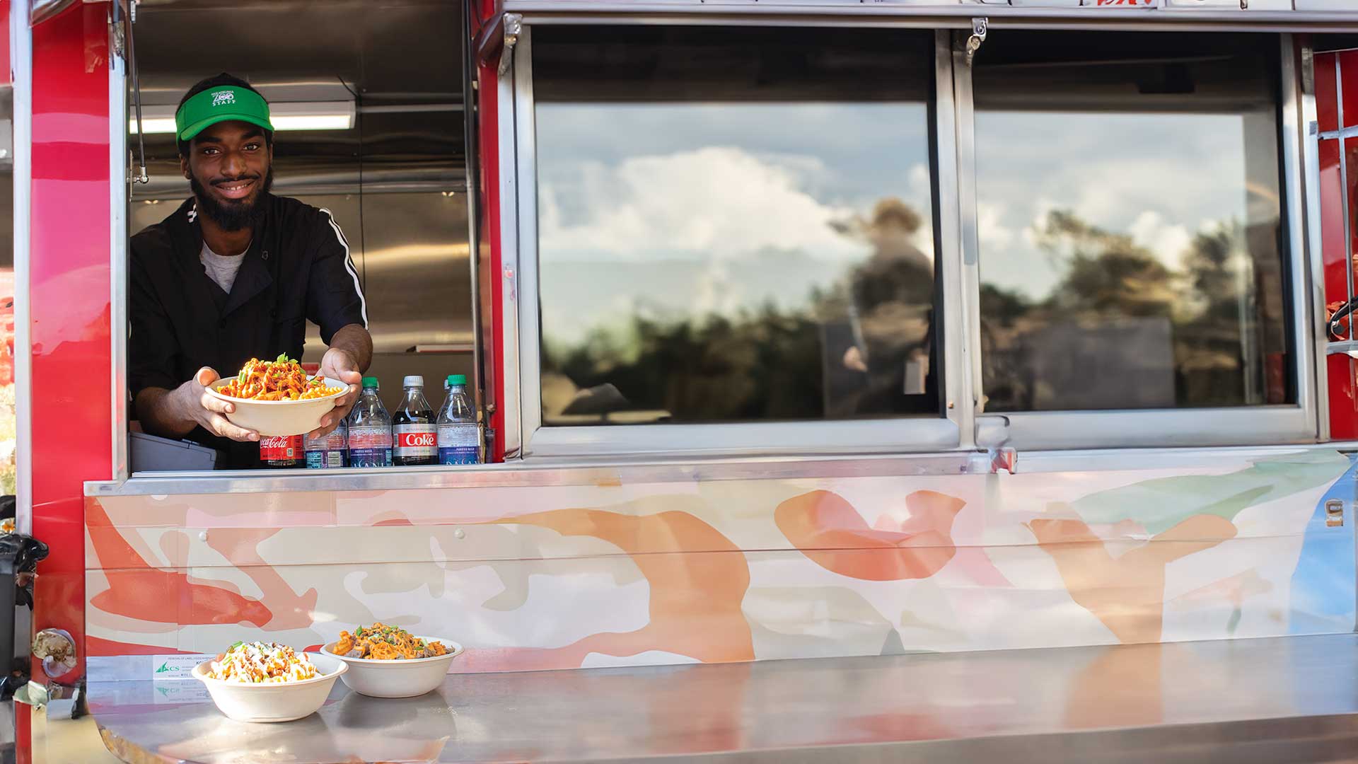 Employee smiling and passing dish through food truck window